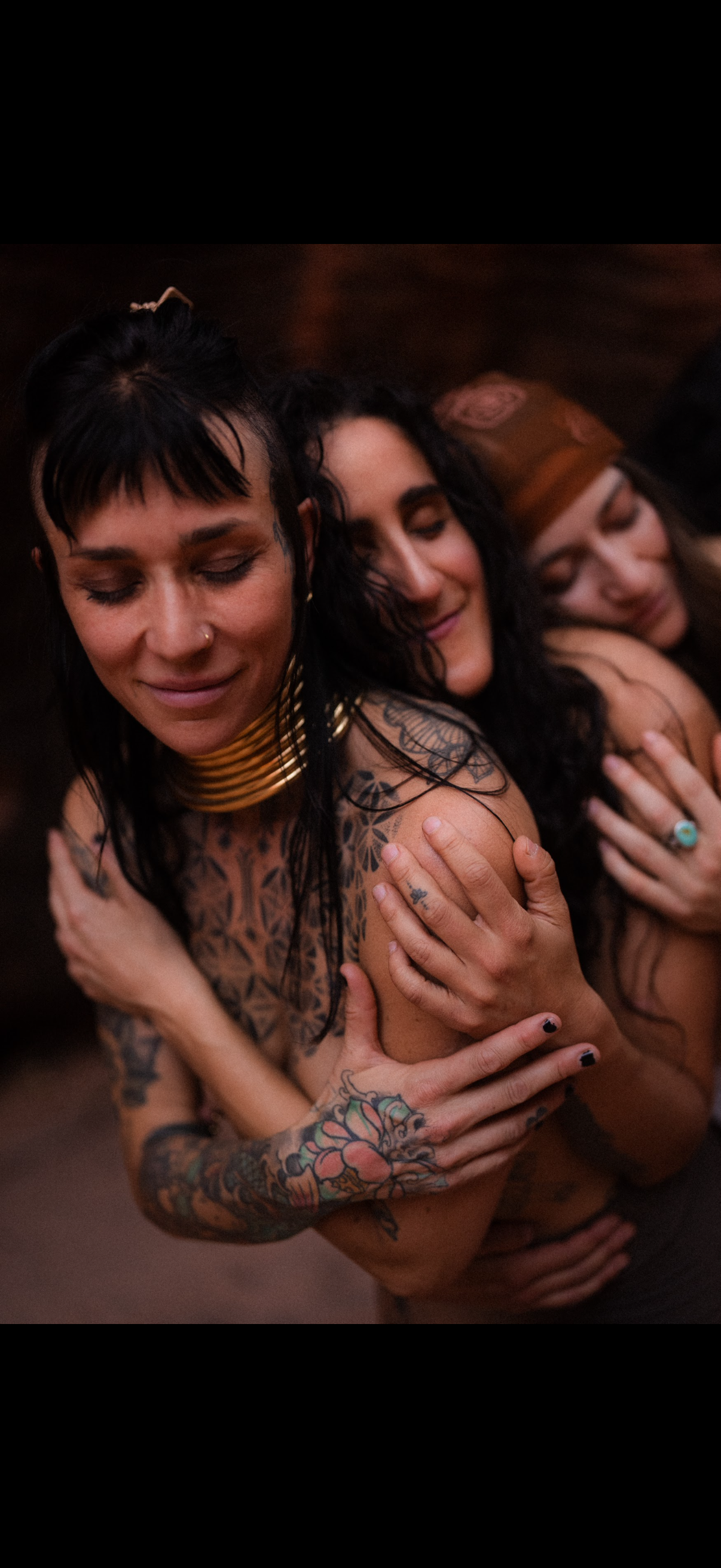 Two women in an intimate embrace, one holding the other from behind