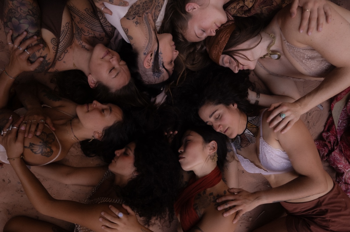 Women lying in a circle together, heads touching, overhead view